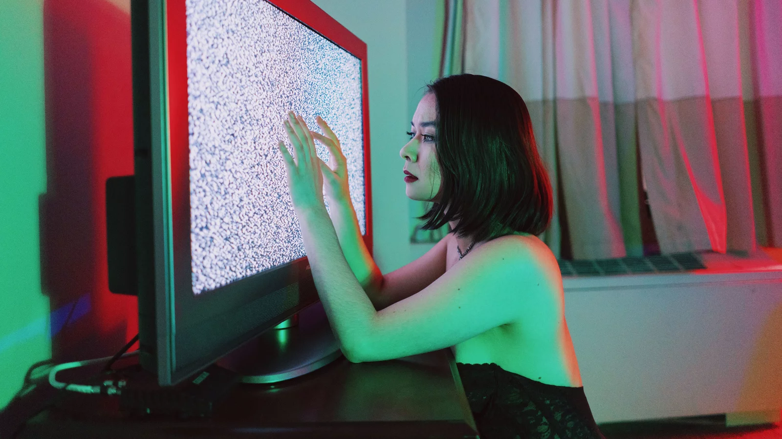 Mitski stares at a TV displaying static noise for a photoshoot. (Ngo, Bao. NPR. August 2018).