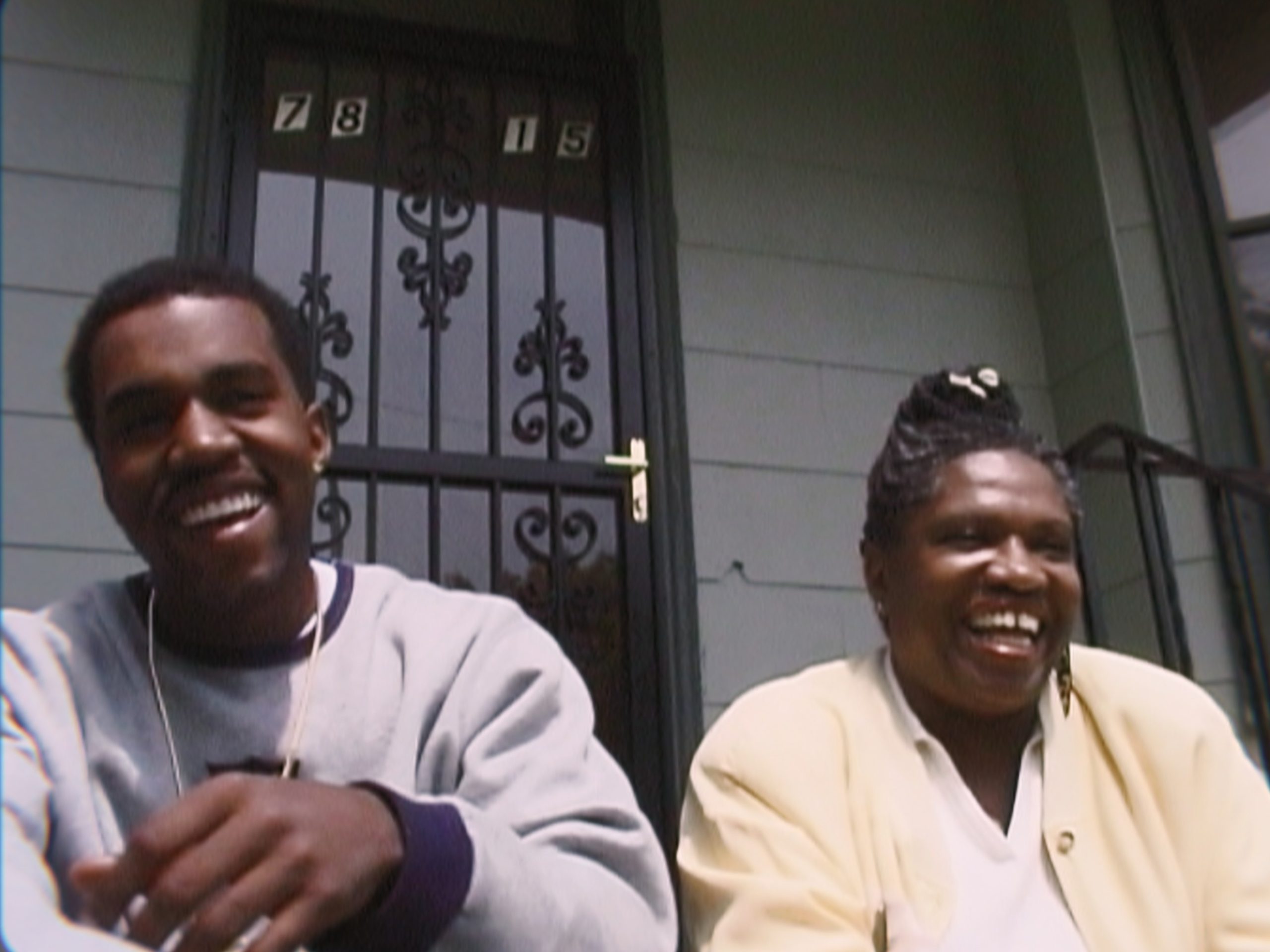 Kanye West and his mother Donda West smiling outside of his childhood home.