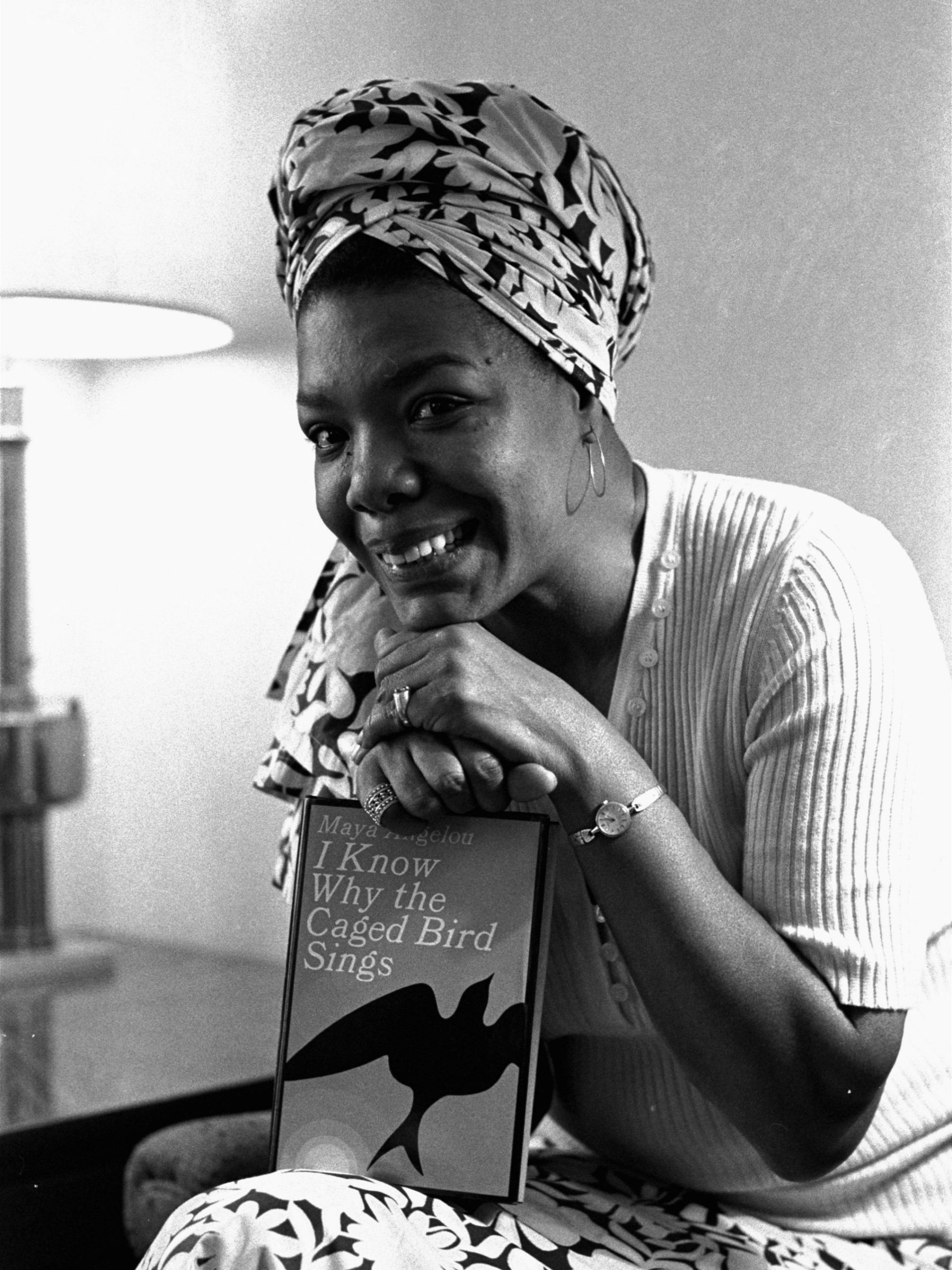 Maya Angelou sits holding a copy of her novel "I Know Why the Caged Bird Sings." 