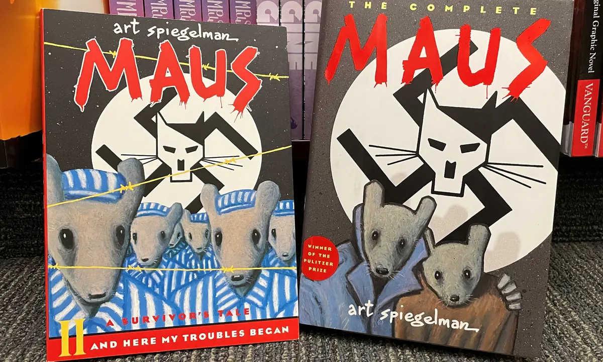 Photo of "Maus" covers which include an illustration of mice sitting below a swastika that has a cartoon cat drawn on it. 