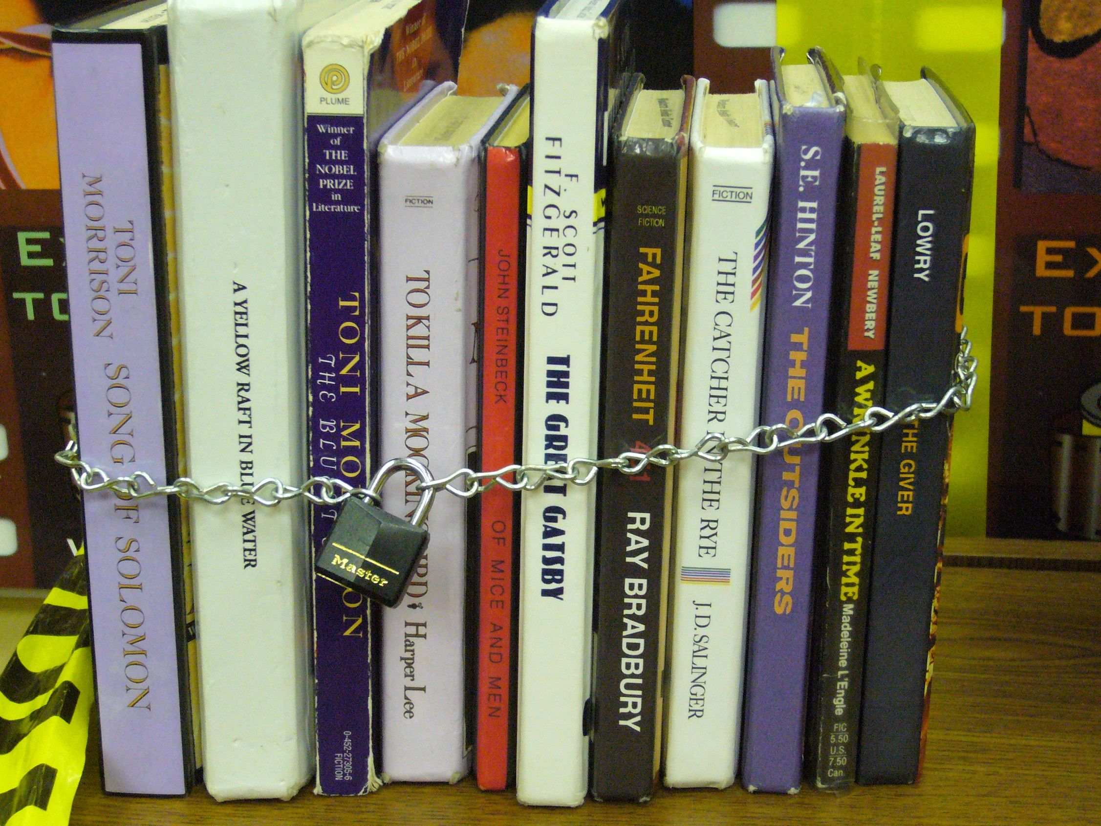 Group of books with a locked chain around them, books included are classics like "The Great Gatsby" and "The Catcher in the Rye."