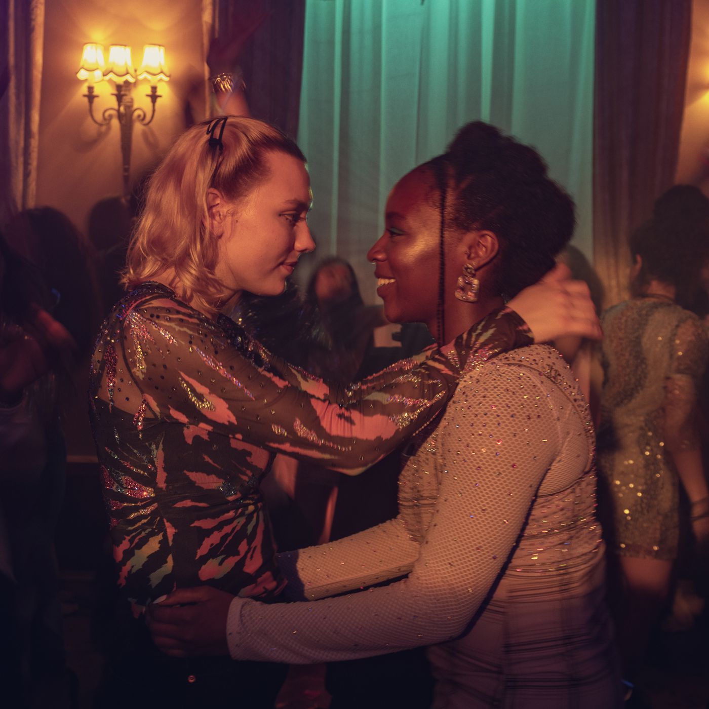 Two characters from "Heartstopper," Darcy and Tara, dancing together at a party. 