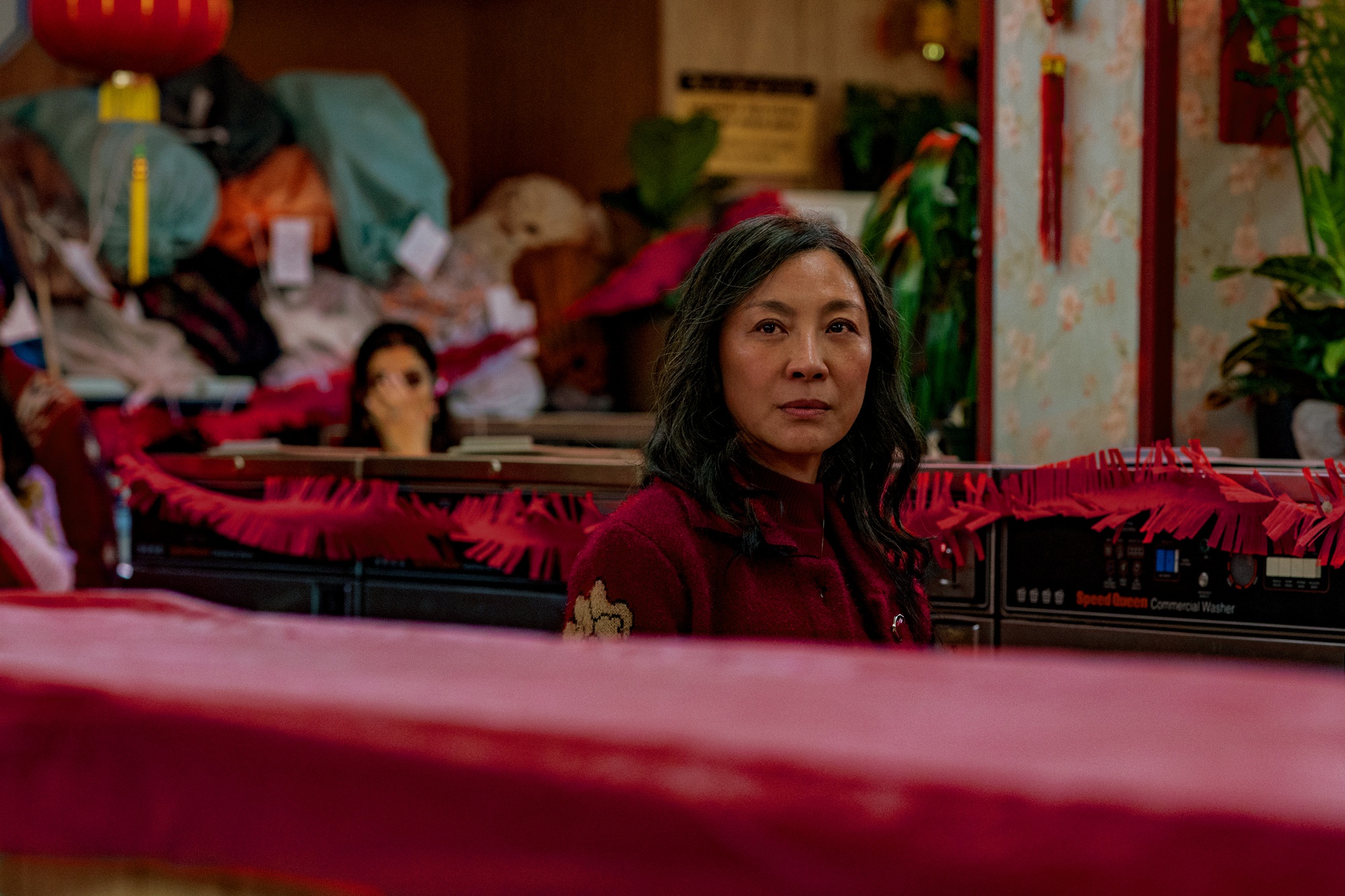 Evelyn (Michelle Yeoh) looks up pensively in her laundromat, which is decorated from Lunar New Year.