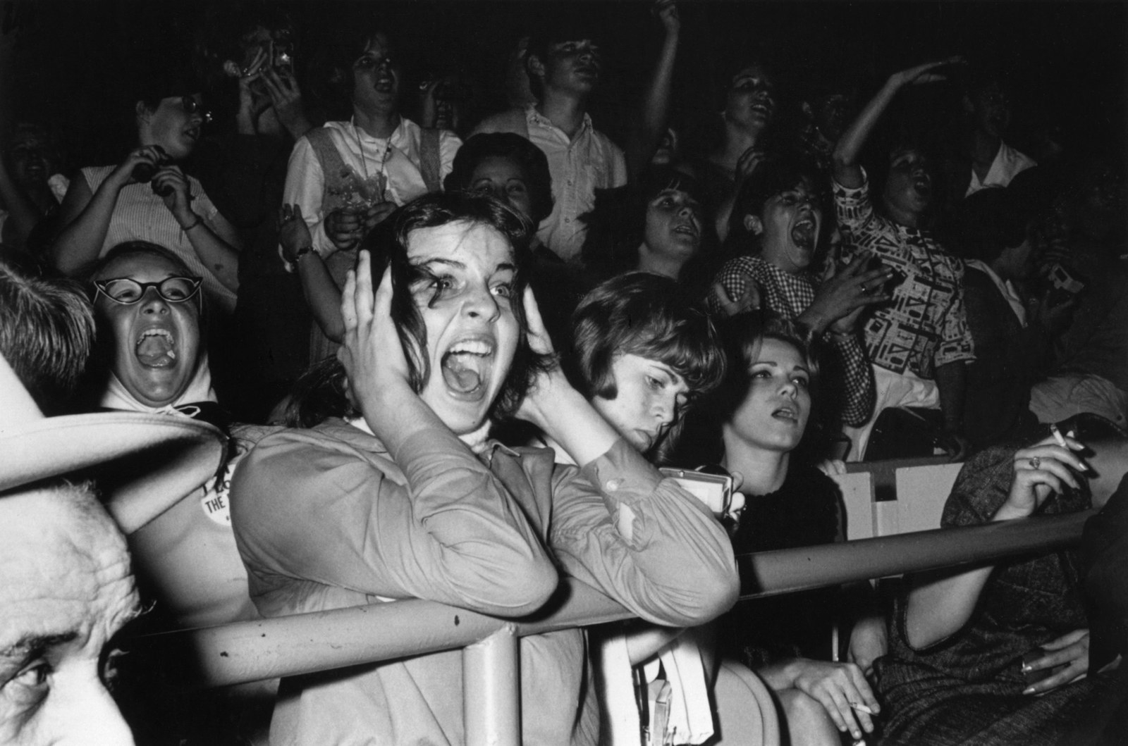 A black and white photo of Beatles fangirls screaming at a performance. 