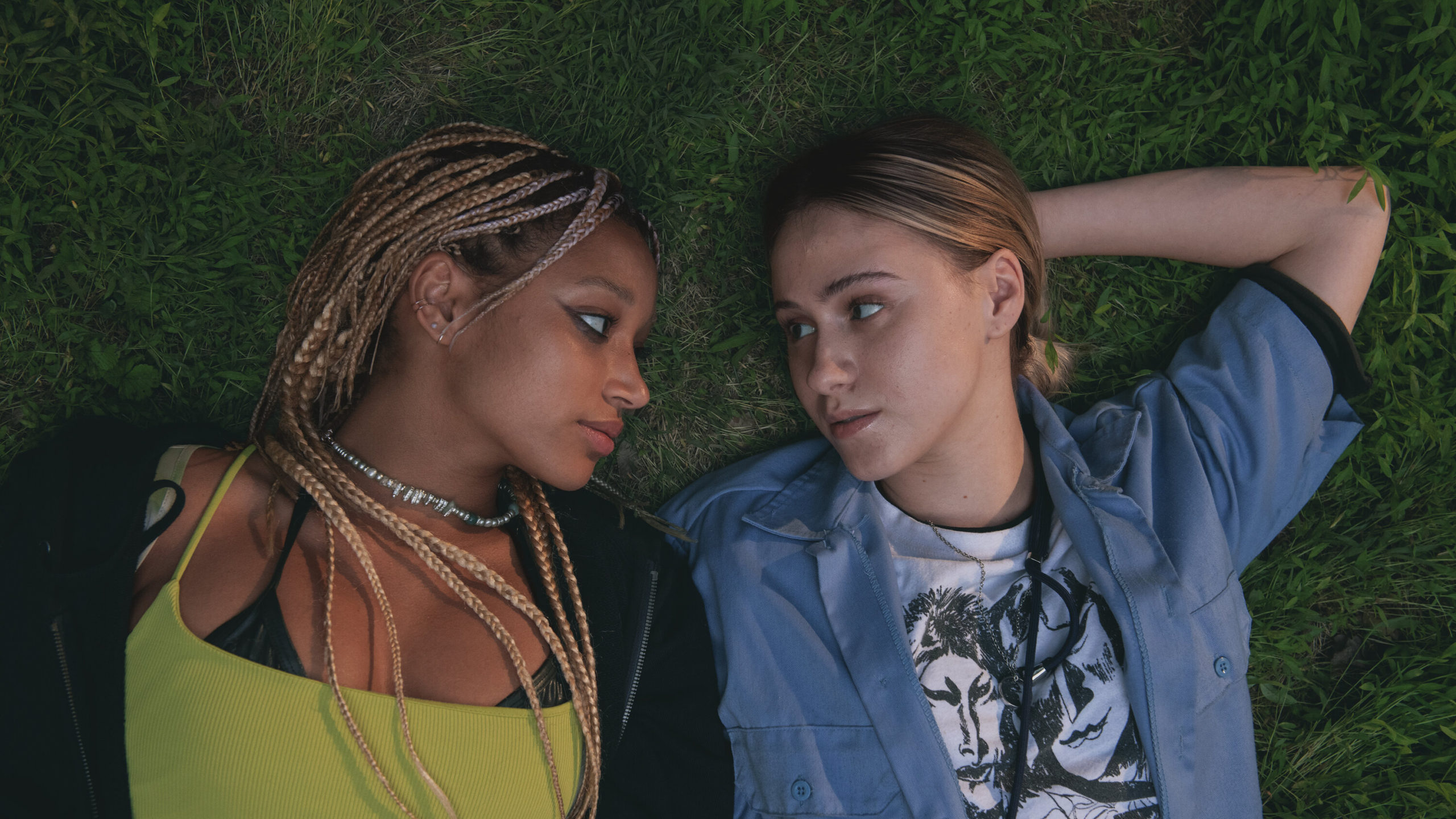 Amandla Stenberg as Sophie and Maria Bakalova as Bee laying on the grass together in Bodies Bodies Bodies (2022).