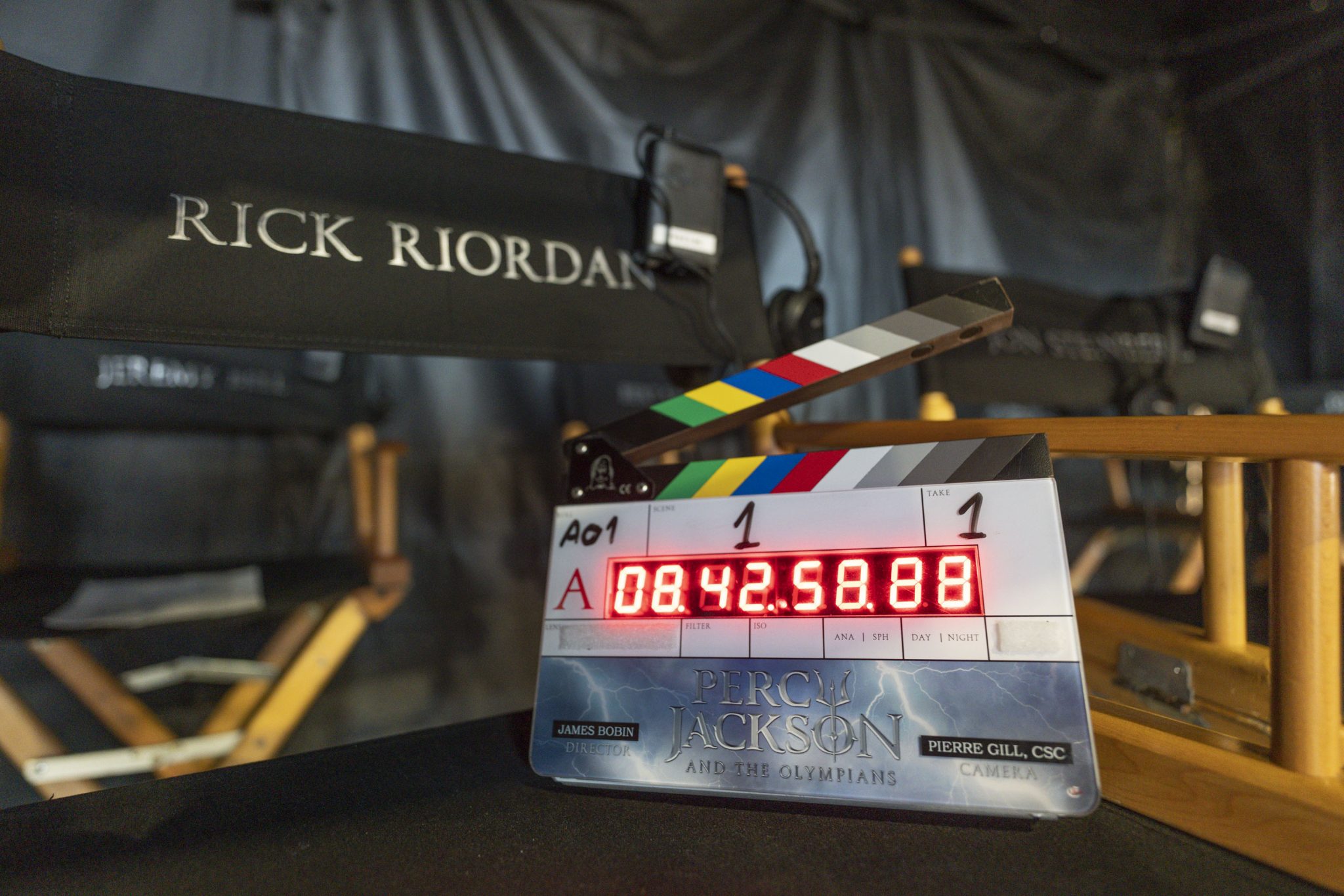 A set marker sits perched on a director's chair that has Rick Riordan's name embroidered on the back.