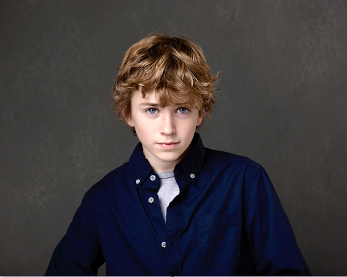 Walker Scobell, a young white boy with blue eyes and sandy blonde hair, stares intently into the acmera.