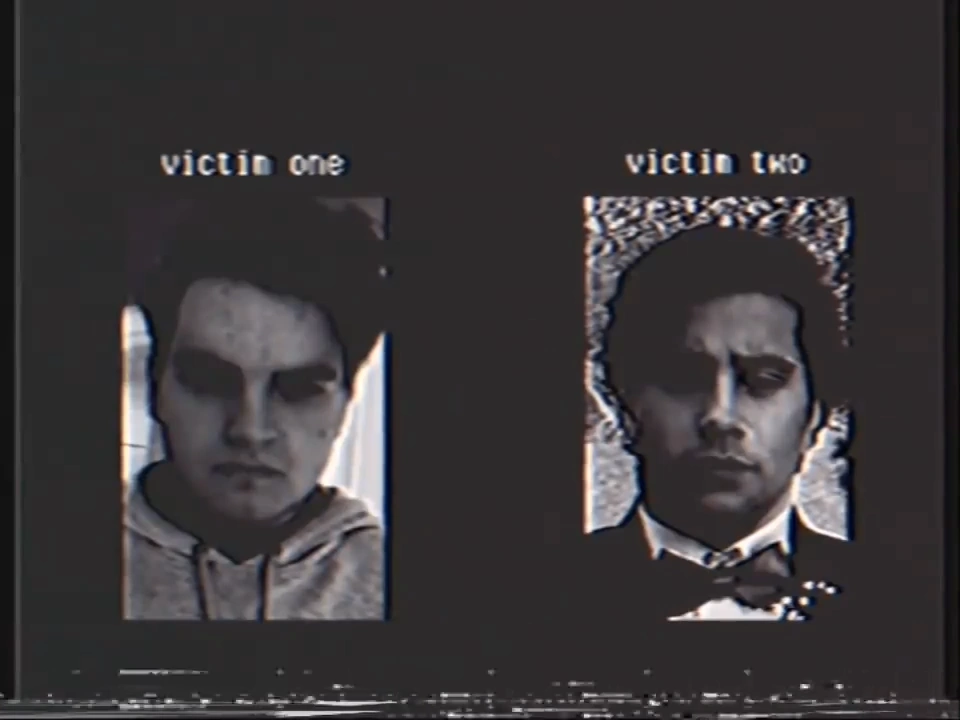 Grainy, slightly distorted black and white image of two men, one in a hoodie and one in a suit and bowtie, labeled "victim one" and "victim two" respectively.