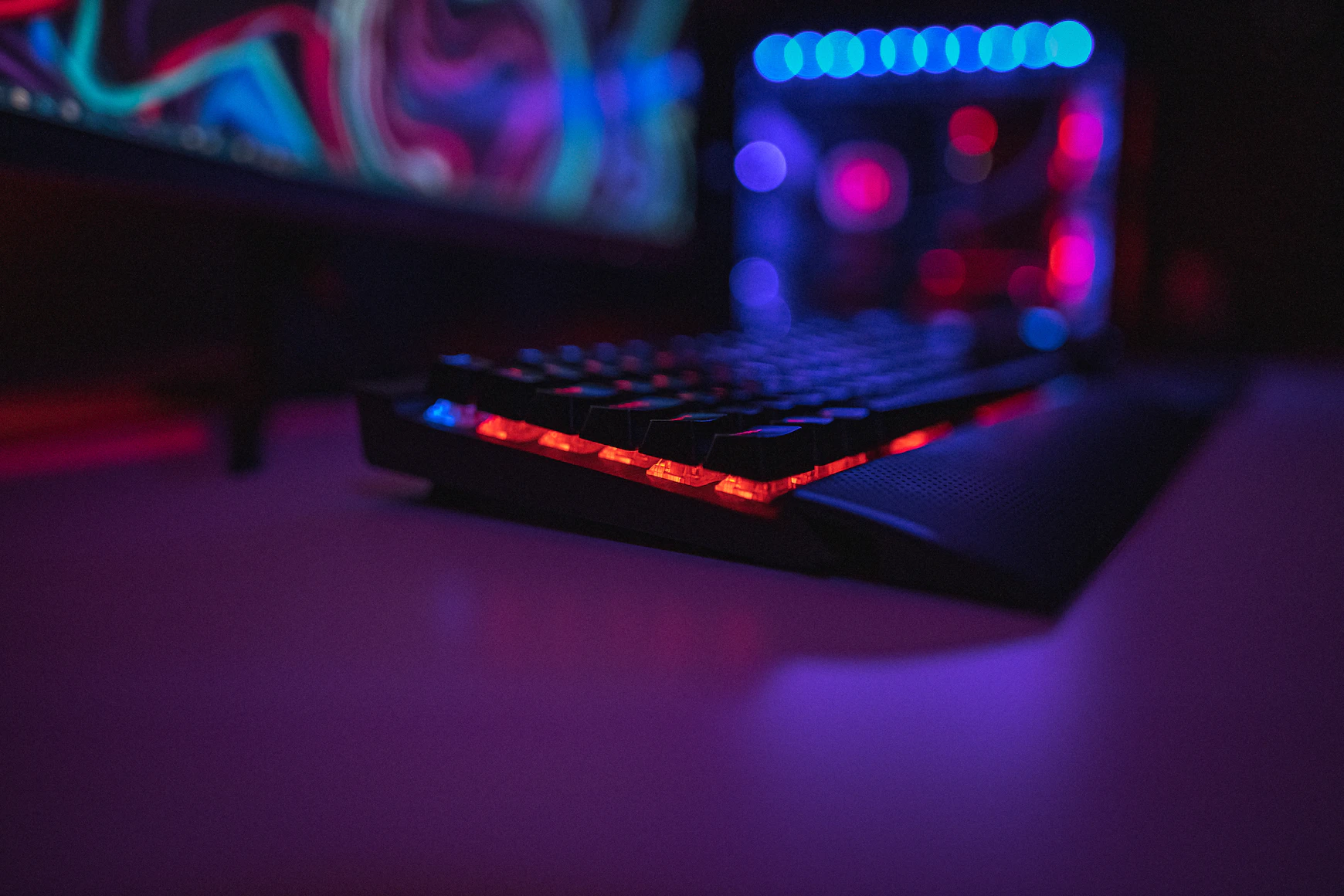 Closeup of a backlit keyboard sitting on a desk in a darkened room.