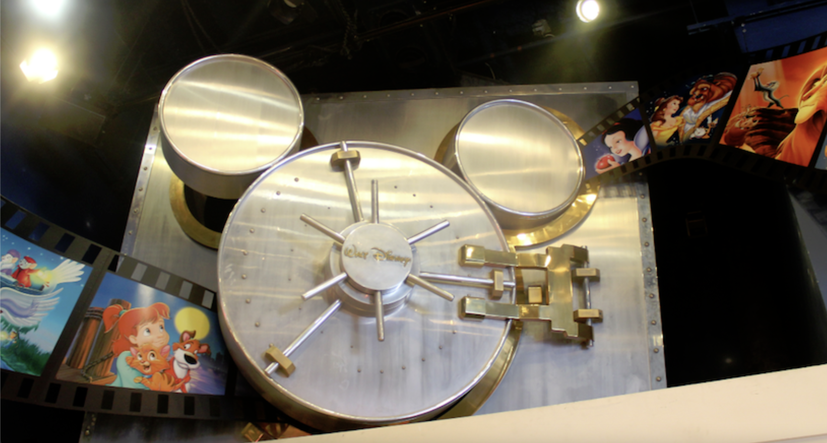 Image of the Disney Vault, a vault shaped like Mickey Mouse, with reels of film entering the slightly-opened door.