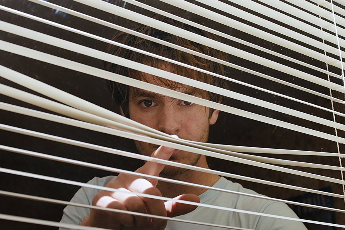 Sam (Andrew Garfield) looking through a window. Mitchell, David Robert. Dir. Under the Silver Lake. 2018.