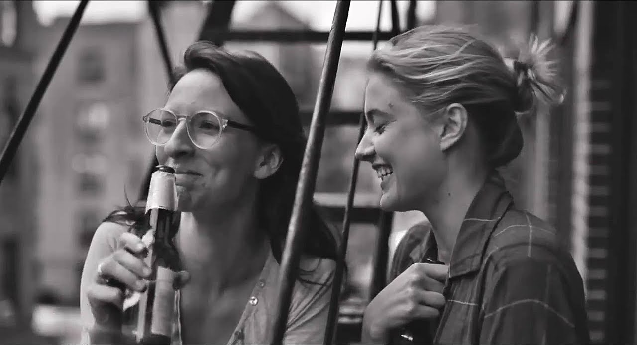 Mickey Sumner as Sophie (left) and Greta Gerwig as Frances (right) enjoying their beers on a fire escape. Baumbach, Noah, Dir. Frances Ha. 2012.