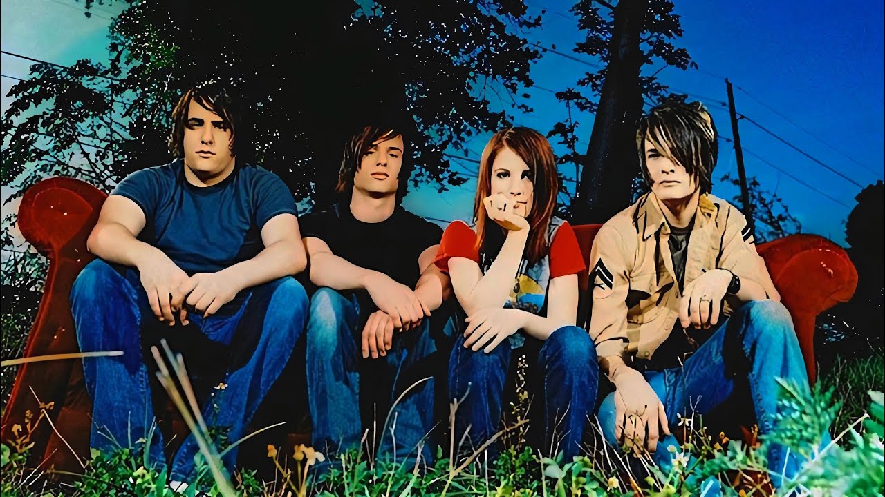 Members of Paramore sit on a red couch in the middle of the forest.  "All We Know Is Falling." Paramore. 2005. Fueled By Ramen. 