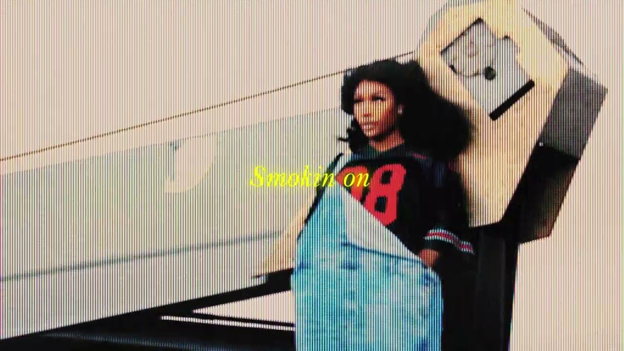 A screenshot from SZA's Lyric Video for "Smoking on my Ex Pack." SZA stands against machinery and looks into the distance.