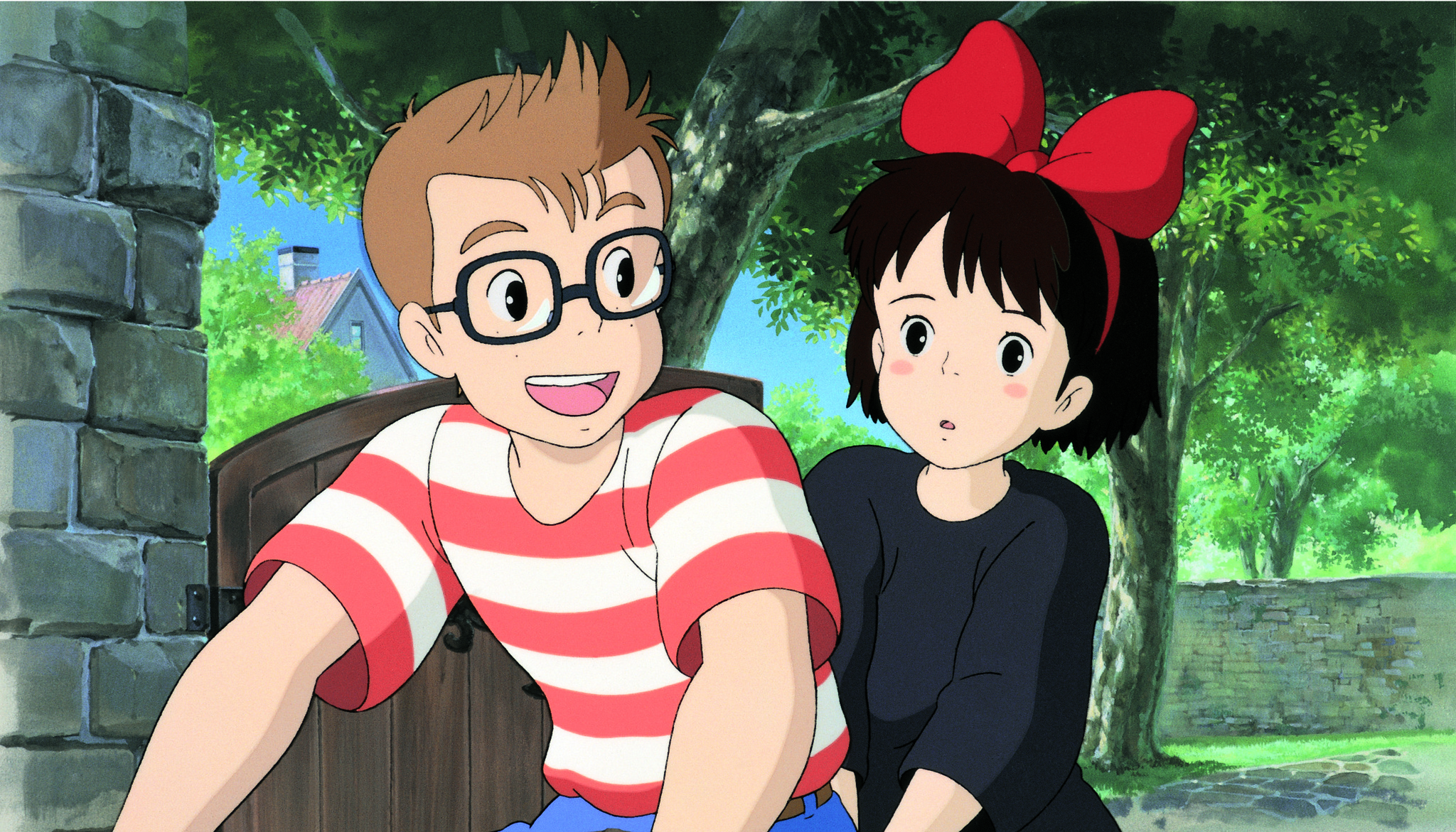 A girl in a black dress and red bow rides on the back of a boy's bike in Kiki's Delivery Service. 