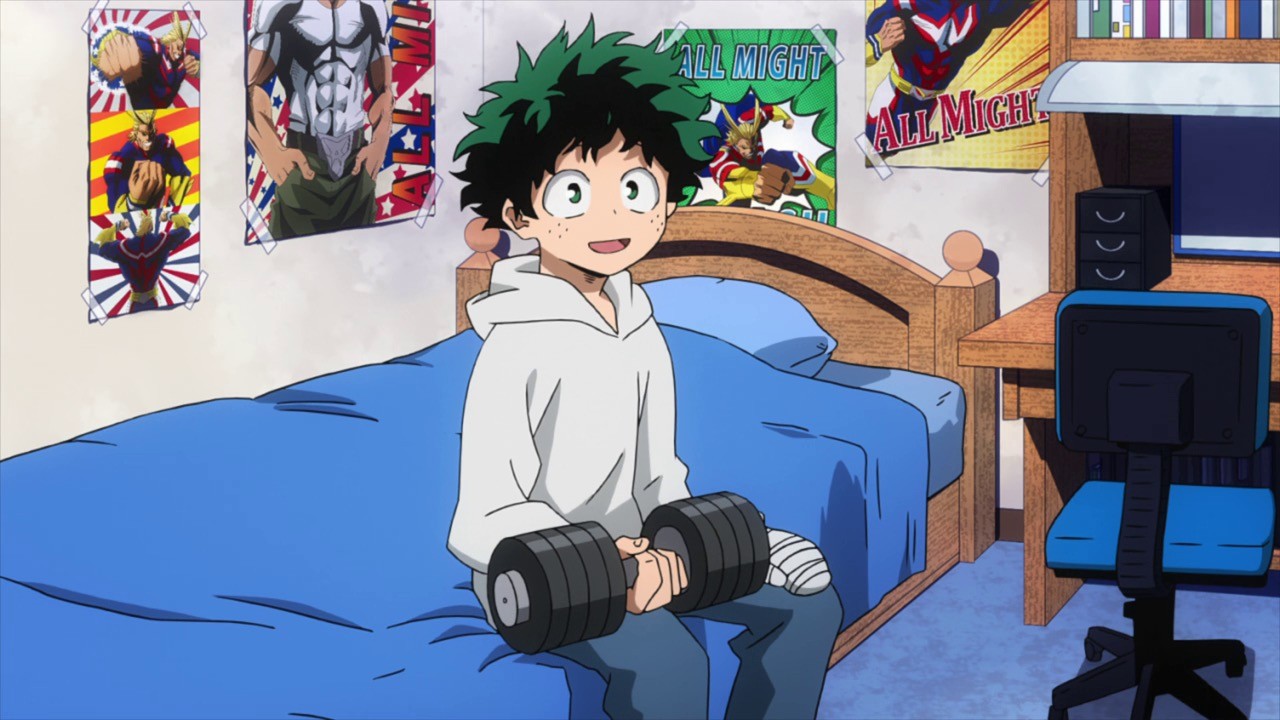 Izuku Midoriya from "My Hero Academia" (2016-) sits on his blue bed in a room full of posters. 