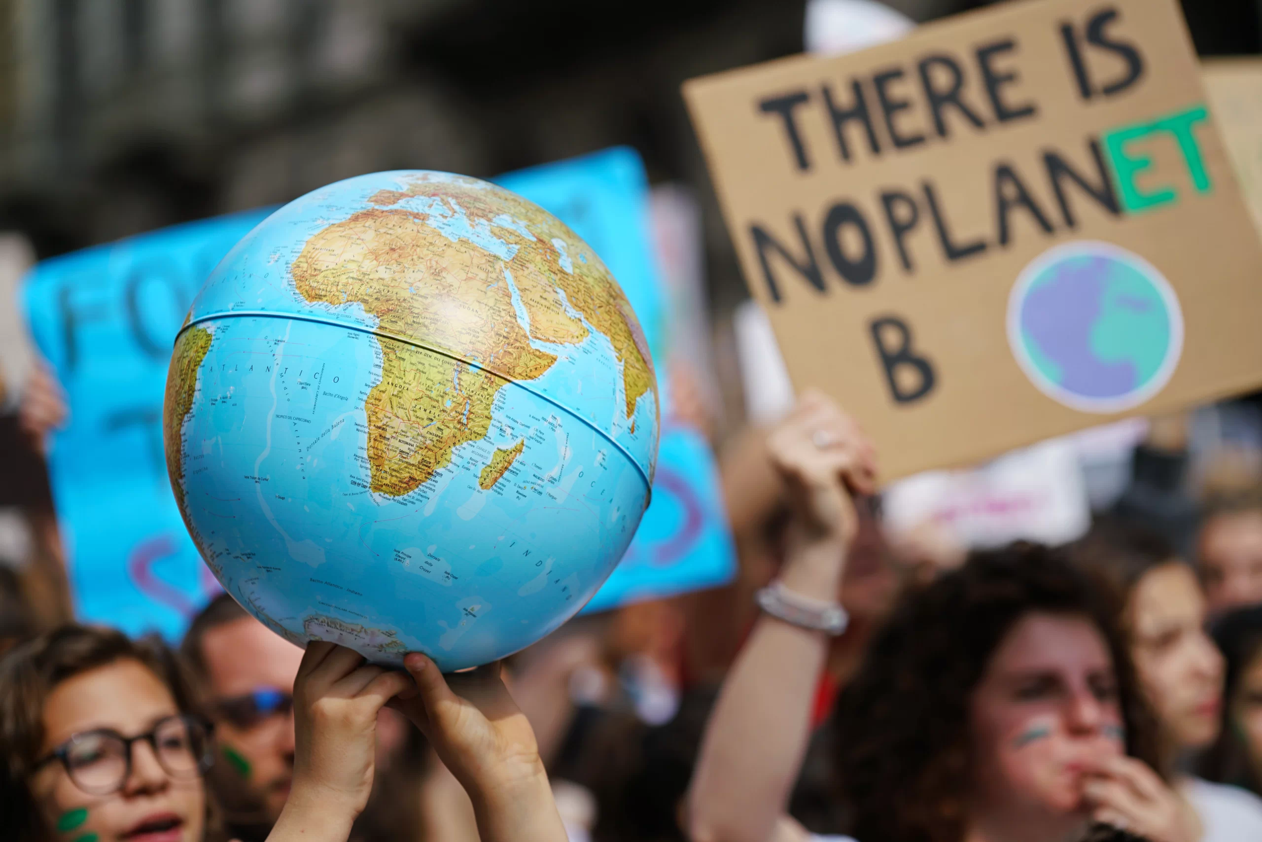 People marching at a Save The Planet march, holding up a globe and a sign that reads “THERE IS NO PLANET B.”