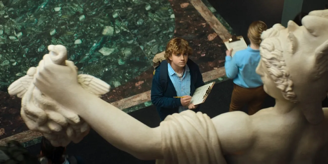 Percy looks up at a statue depicting the demigod Perseus from Greek mythology. 