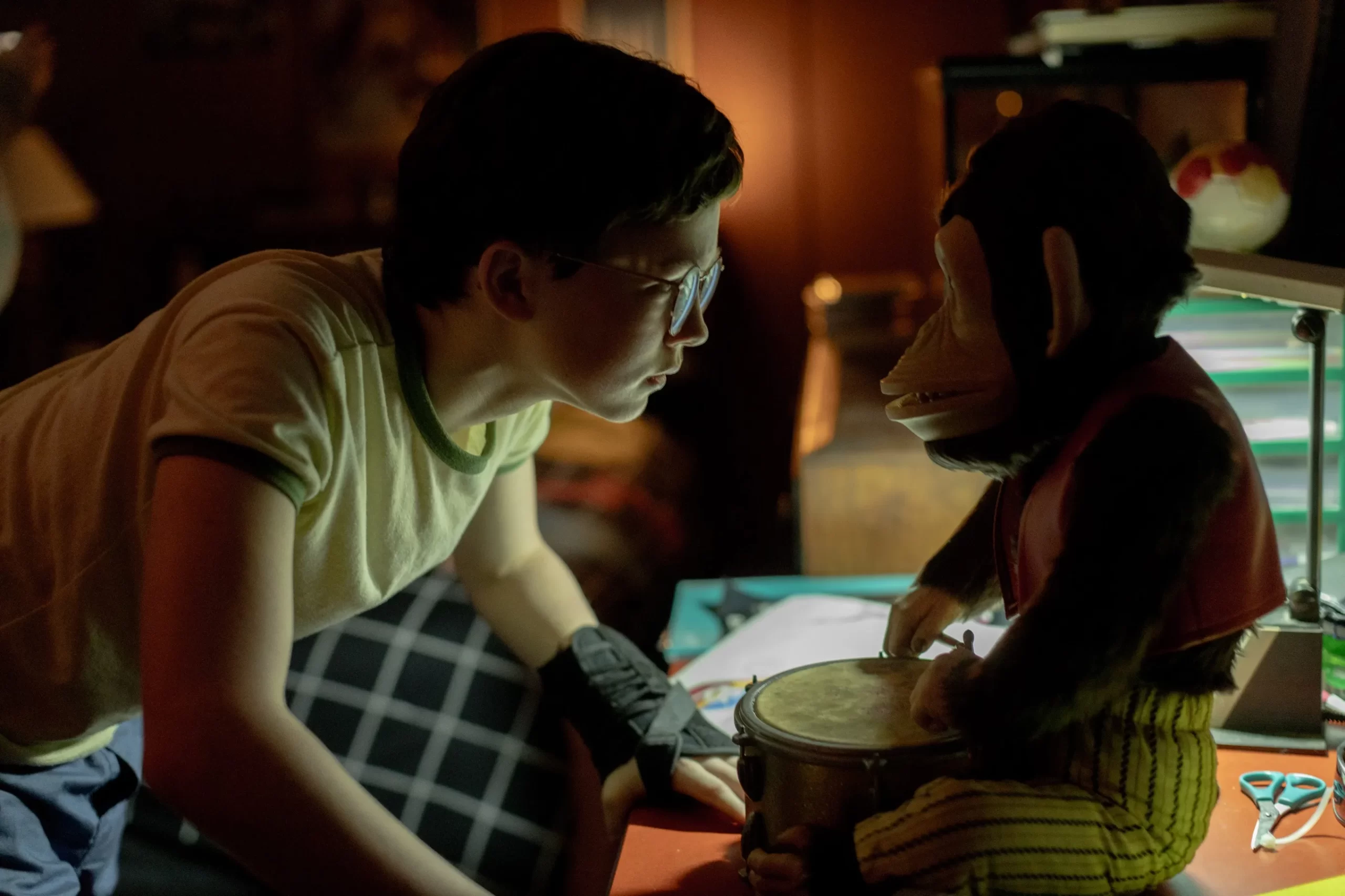 Young Hal sits facing the monkey. Perkins, Osgood. The Monkey, 2025.