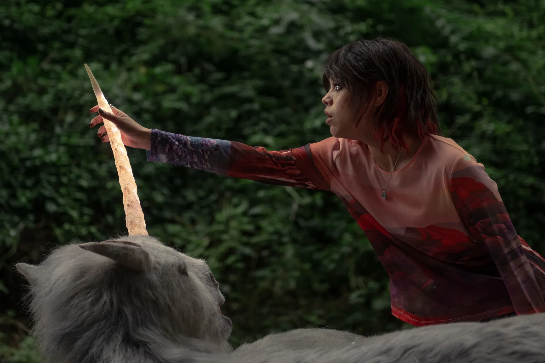 Ridley (Jenna Ortega) touches a glowing unicorn's horn. Scharfman, Alex. Death of a Unicorn. 2025.