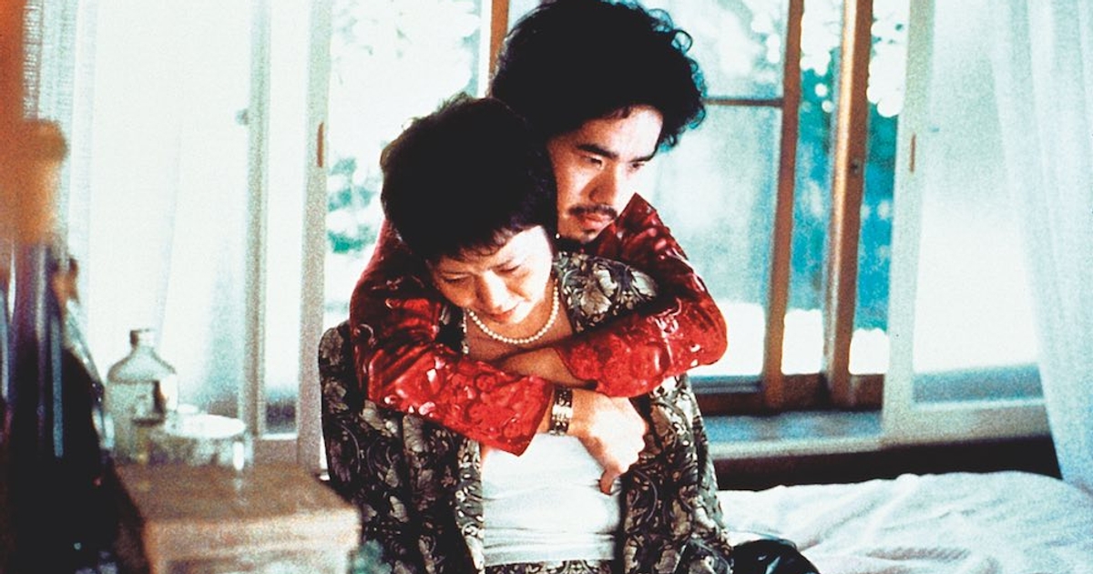 Miike, Takashi. Visitor Q. 2001. Man embraces woman from behind.