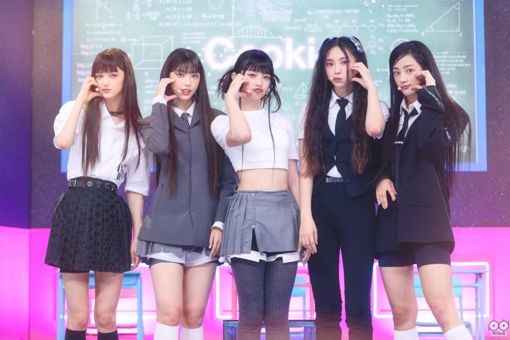 NJZ members Danielle, Haerin, Hanni, Hyein, and Minji making cheek hearts at Inkigayo.