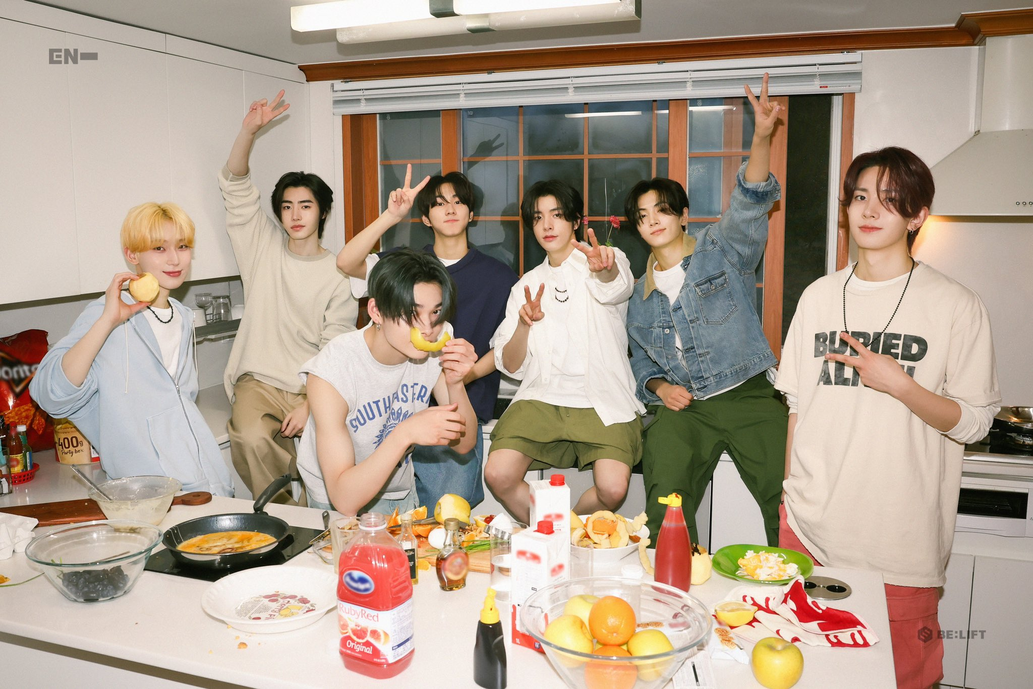 ENHYPEN members Sunoo, Sunghoon, Ni-Ki, Jungwon, Jake, Jay, and Heeseung pose in front of food.