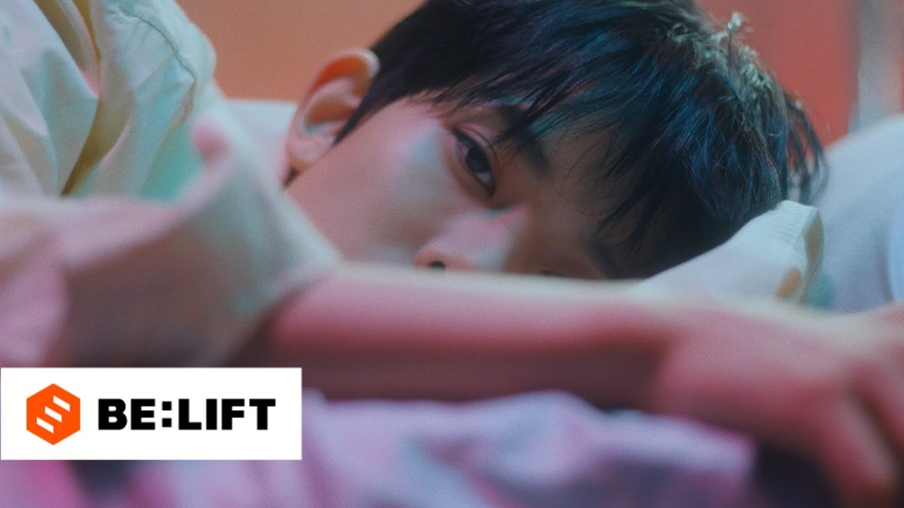 ENHYPEN member Heeseung laying in bed staring at the camera