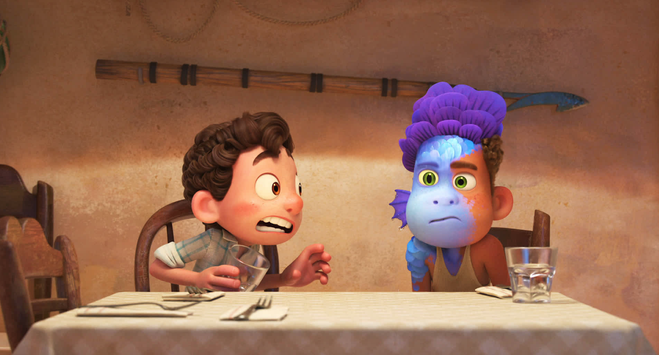 At the dinner table, Luca stares in shock at Alberto half of whose face is in sea monster form after being splashed with water.