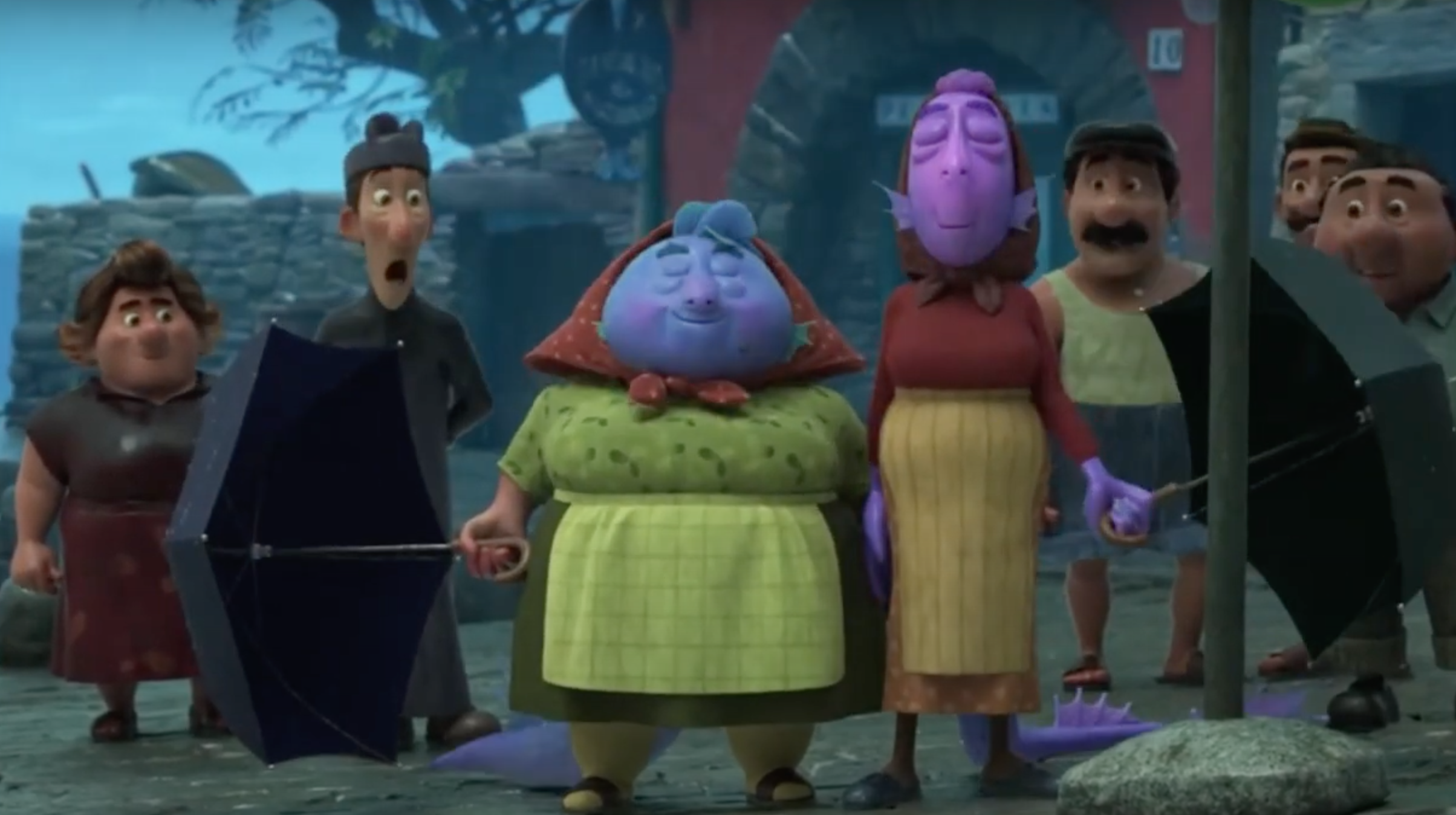 Two women stand side by side and lower their umbrellas to reveal their sea monster form to the surprised townspeople nearby.