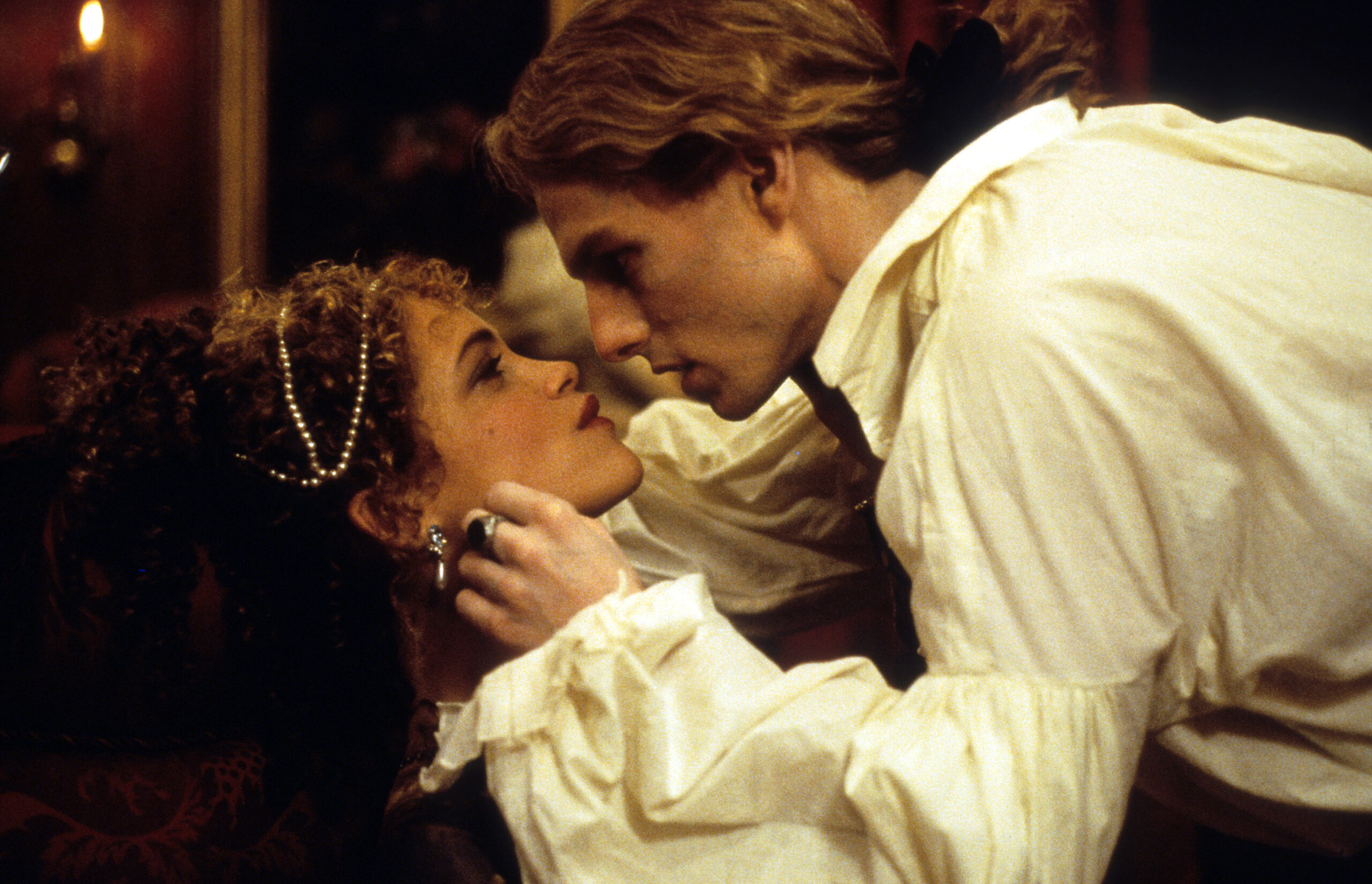 A vampire and a woman almost kiss in a Gothic setting.