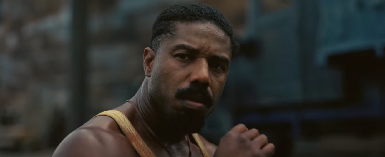 A bloody Smoke (Michael B. Jordan) sits outside the juke joint.
