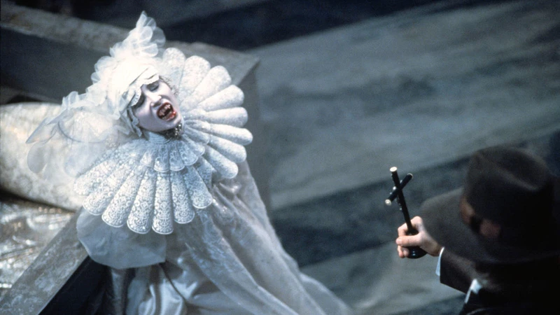 A vampire hunter holds a cross up to a vampire.