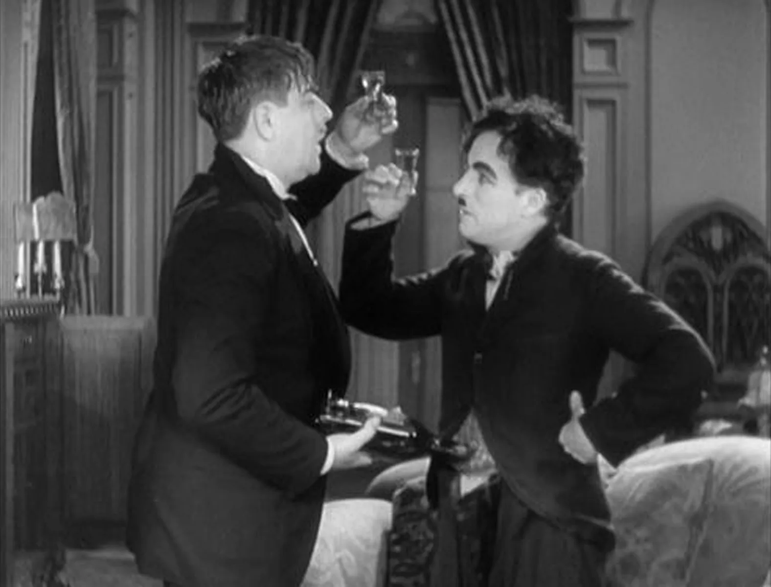 Charlie Chaplin and Harry Myers in the movie City Lights raising a toast to each other.
