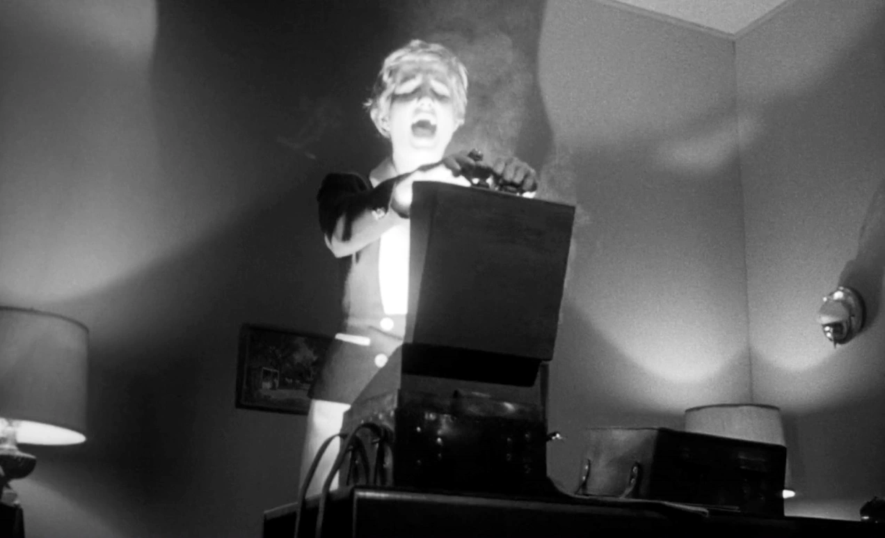 Lily opening the box at the end of Kiss Me Deadly with fear in her eyes. 