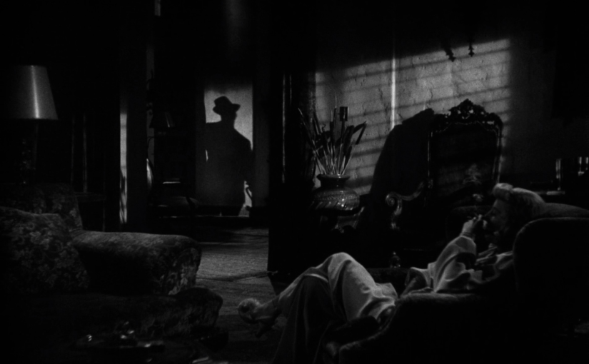 Phyllis lounges in the dark, smoking in her robe, as the shadow of Walter approaches in the doorway.