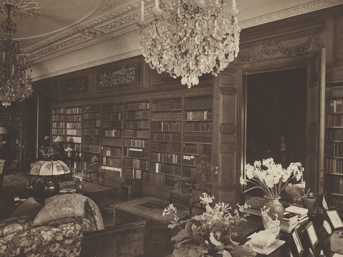 Amy Lowell's personal home library with well-stocked shelves and decorations such as elaborate chandeliers and elegant lamps, rugs, and flower vases.