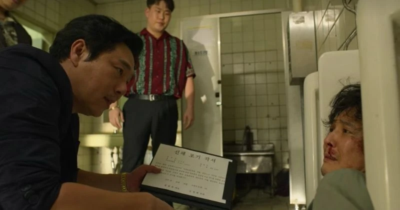Gi-hun getting jumped in the bathroom and forced to sign a document with the blood from his nose.
