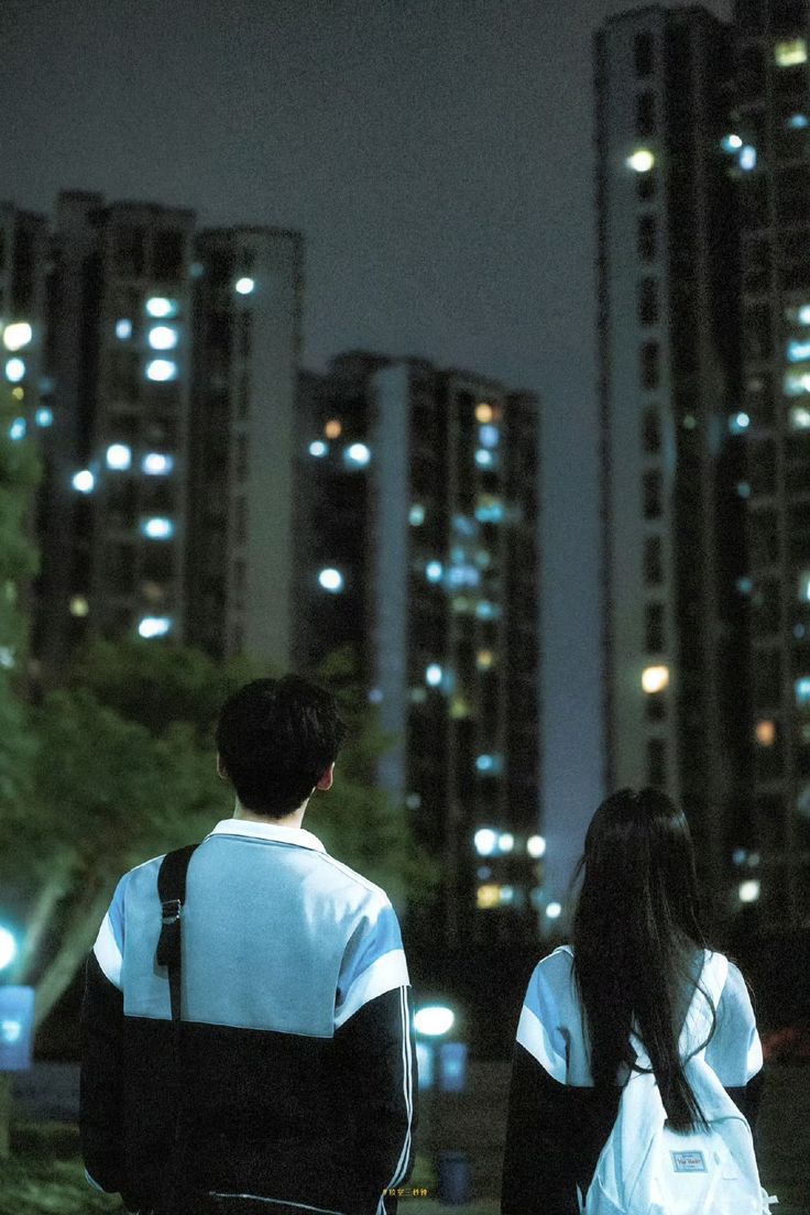 A teenage boy (a younger version of Sang Yan from The First Frost) and a teenage girl (a younger version of Wen Yifan from The First Frost) gaze up at the night sky and skyscrapers.