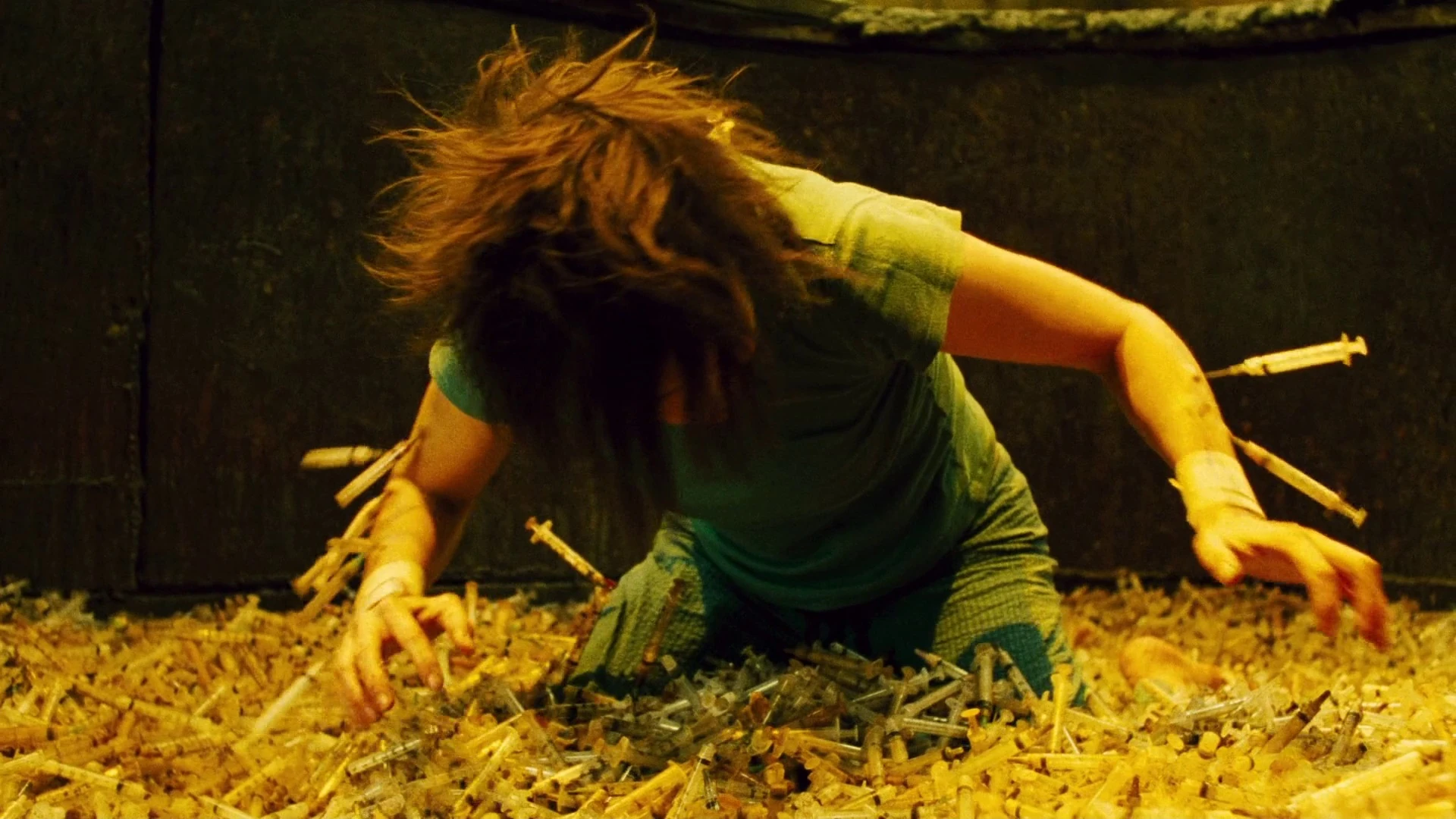 Amanda Young, played by Shawnee Smith, kneeling in a pit of needles. Several of them stick out of her arms. Bousman, Darren Lynn, dir. Saw II. 2005.
