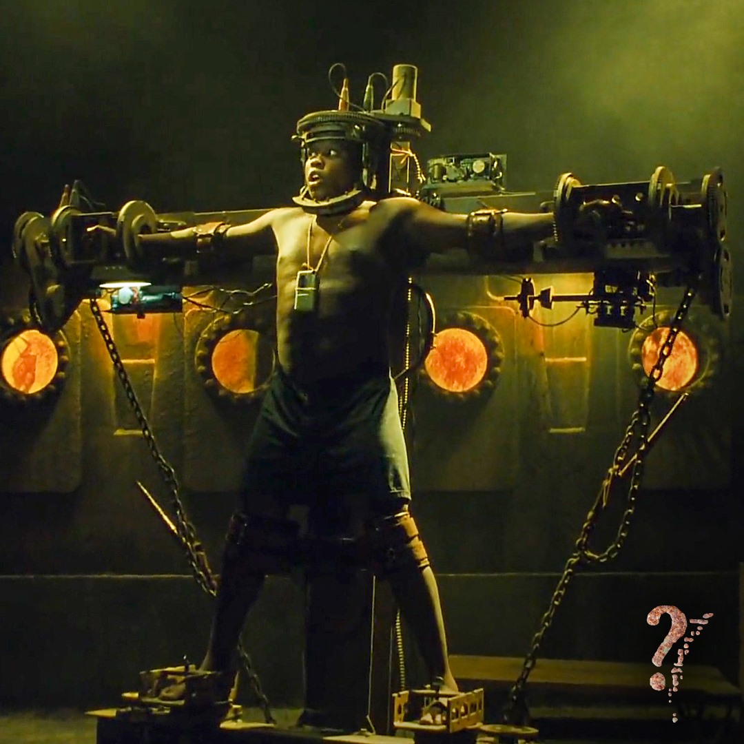 Jigsaw victim Timothy Young, played by Mpho Koaho, pleads for help in The Rack trap. A tape recorder is tied to his chest. Bousman, Darren Lynn, dir. Saw III. 2006.