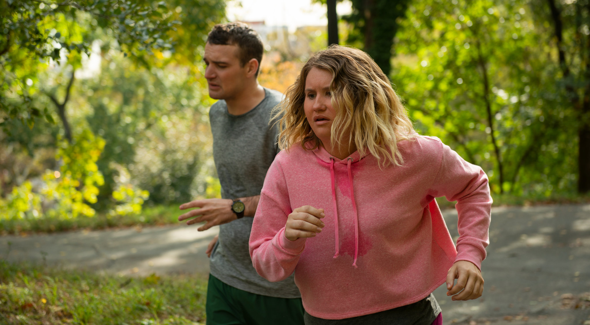 New Resolutions. Brittany and Seth, played by Micah Stock, push through their troubles running together. The shot is a medium close-up as the two struggle to run from the back of the group. They are sweating and disheveled, but moving along slowly.