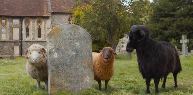 Mopple, Lily, and Sebastian from The Sheep Detectives gathered in the church's cemetery, standing beside a blank tombstone.