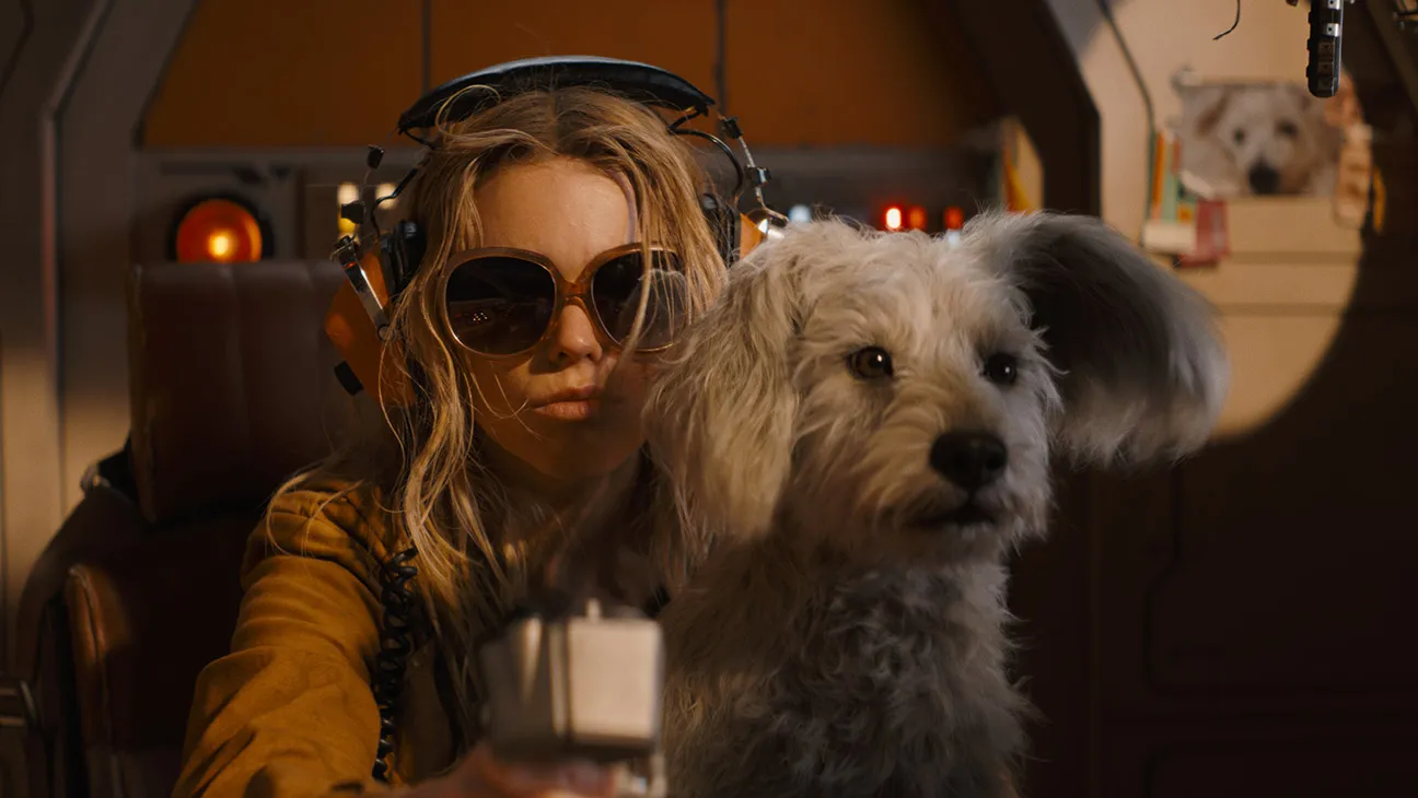 Krypto sits on Kara's lap on the pilot seat. Gillespie, Craig. Supergirl. DC Studios, 2026.