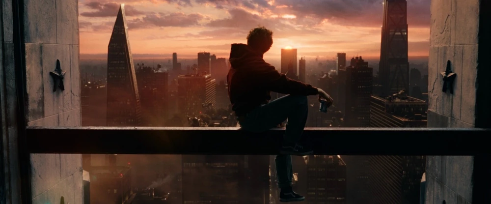 Peter Parker watching the sun rise on the horizon from the top of a skyscraper.