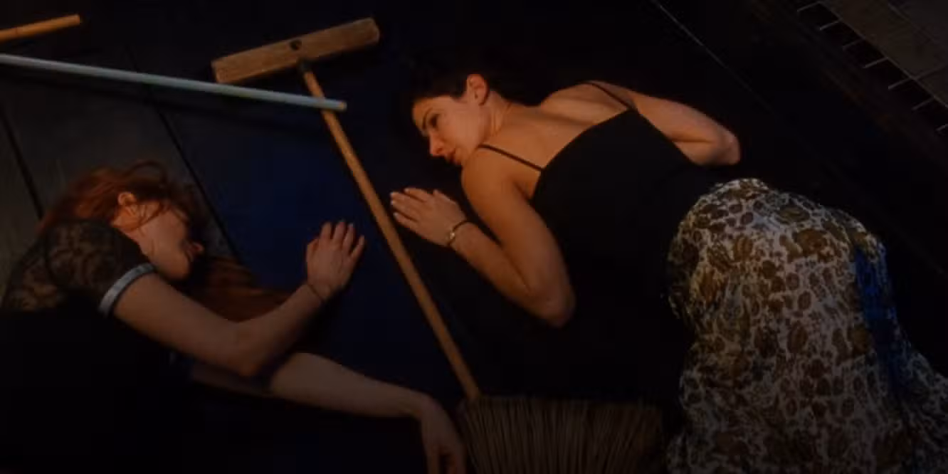 Practical Magic's Gillian and Sally laying on the floor. Gillian is in the broom circle unconscious while Sally has her face turned toward her sister.