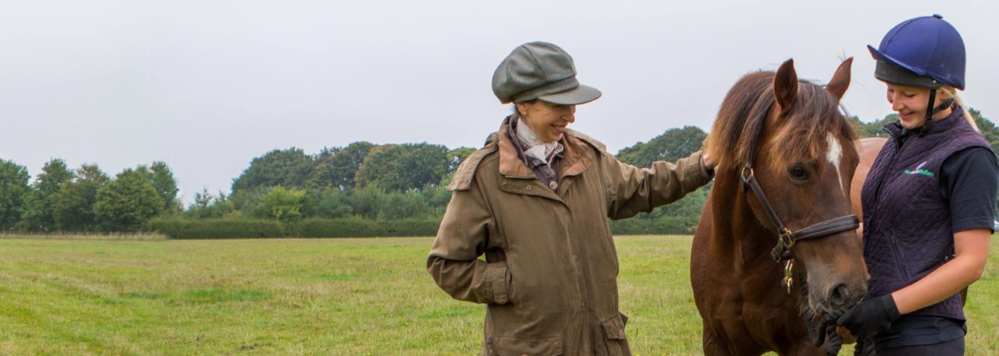 World Horse Welfare Trustee and President, Princess Anne, patting chestnut pony held by groom