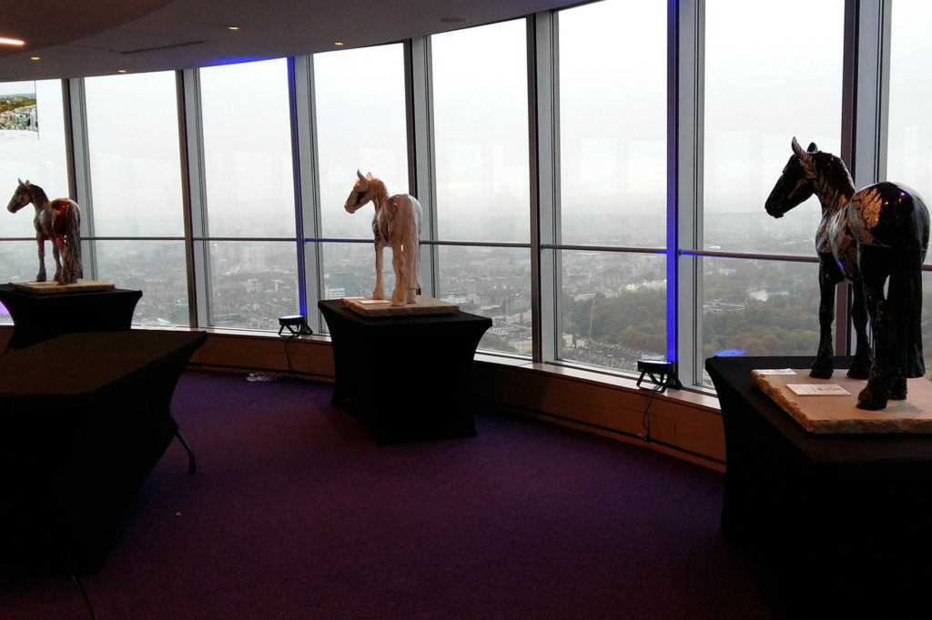 Painted horse sculptures stood in front of tall glass windows looking out over London