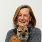 Lady wearing grey jumper and holding Border Terrier