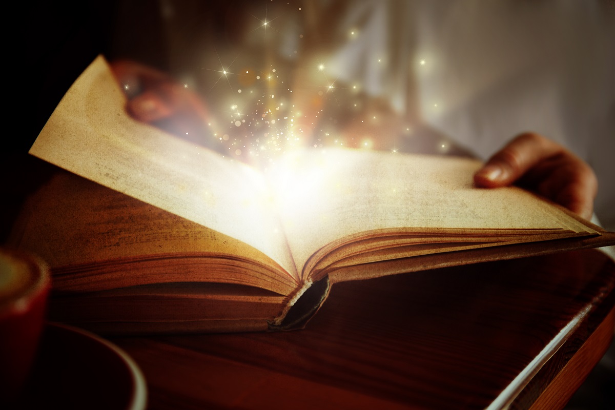 Woman reading shiny magic book, closeup view
